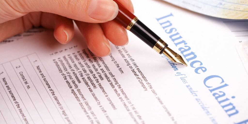 hand filling in insurance claim form