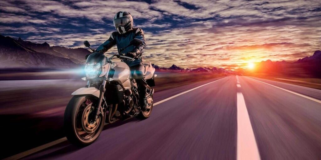 motorcyclist rides home in the evening on a highway while sunset